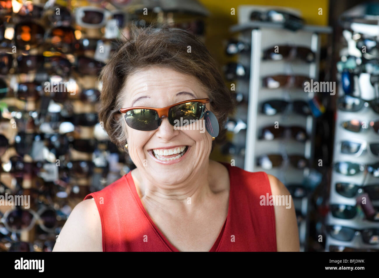 Ältere Frau, die versucht auf Sonnenbrillen, lächelnd Stockfoto