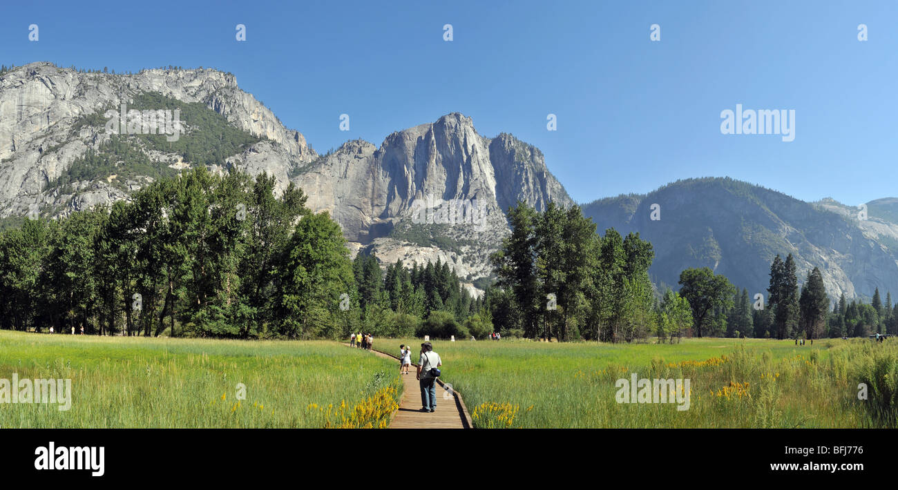 An einem klaren Morgen im August erfreut eine kleine Gruppe von Touristen sich die Wiesen des Yosemite Valley und die Ansichten der Kathedrale Felsen Stockfoto