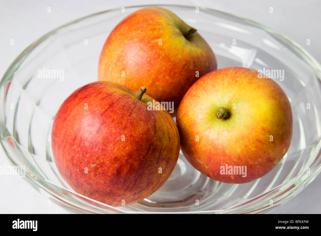 Drei englische Cox Äpfel in eine Glasschüssel Stockfoto