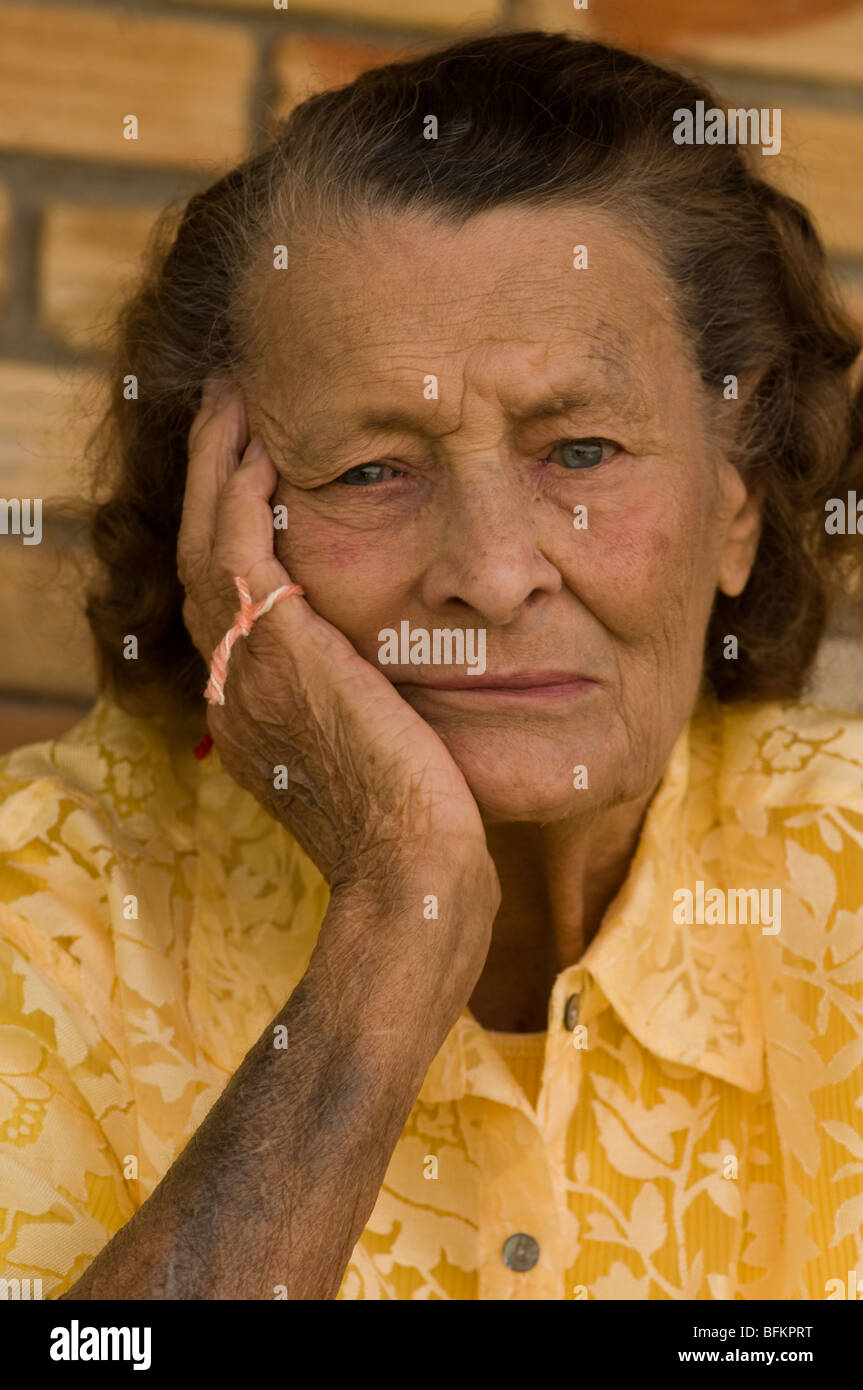 vertikale senior kaukasischen Frau mit Kopf in der Hand und Zeichenfolge an den Fingern, die sich Fragen, was sie vergessen Stockfoto