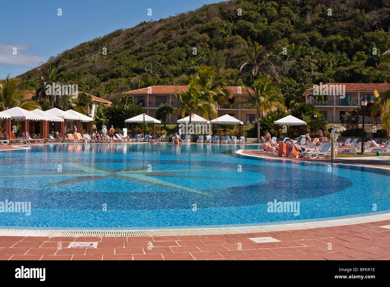 Menschen, die Ruhe am Pool in einem karibischen Resort, Kuba, windgeschützt durch den Berg hinter Stockfoto