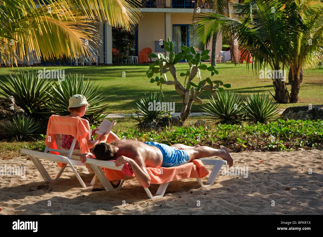 Ein paar entspannte in einem Resort. Frau ist ein Buch lesen, Mann, die Festlegung von Gerben, Karibik Resort Stockfoto