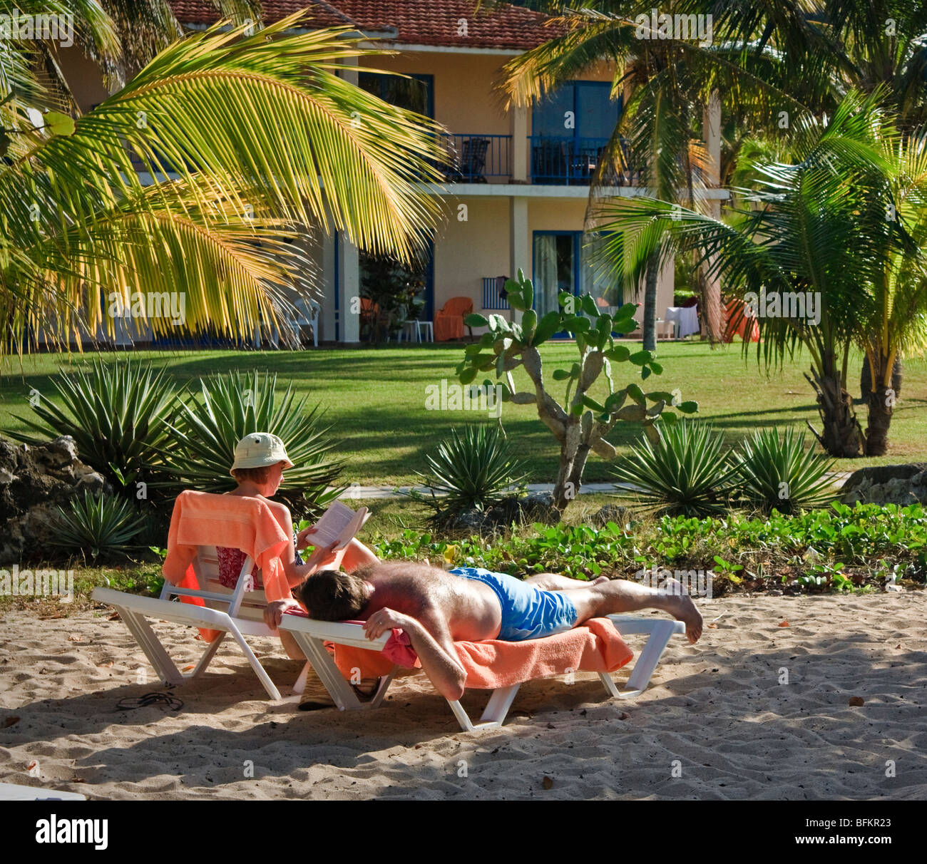 Ein paar entspannte in einem Resort. Frau ist ein Buch lesen, Mann, die Festlegung von Gerben, Karibik Resort Stockfoto