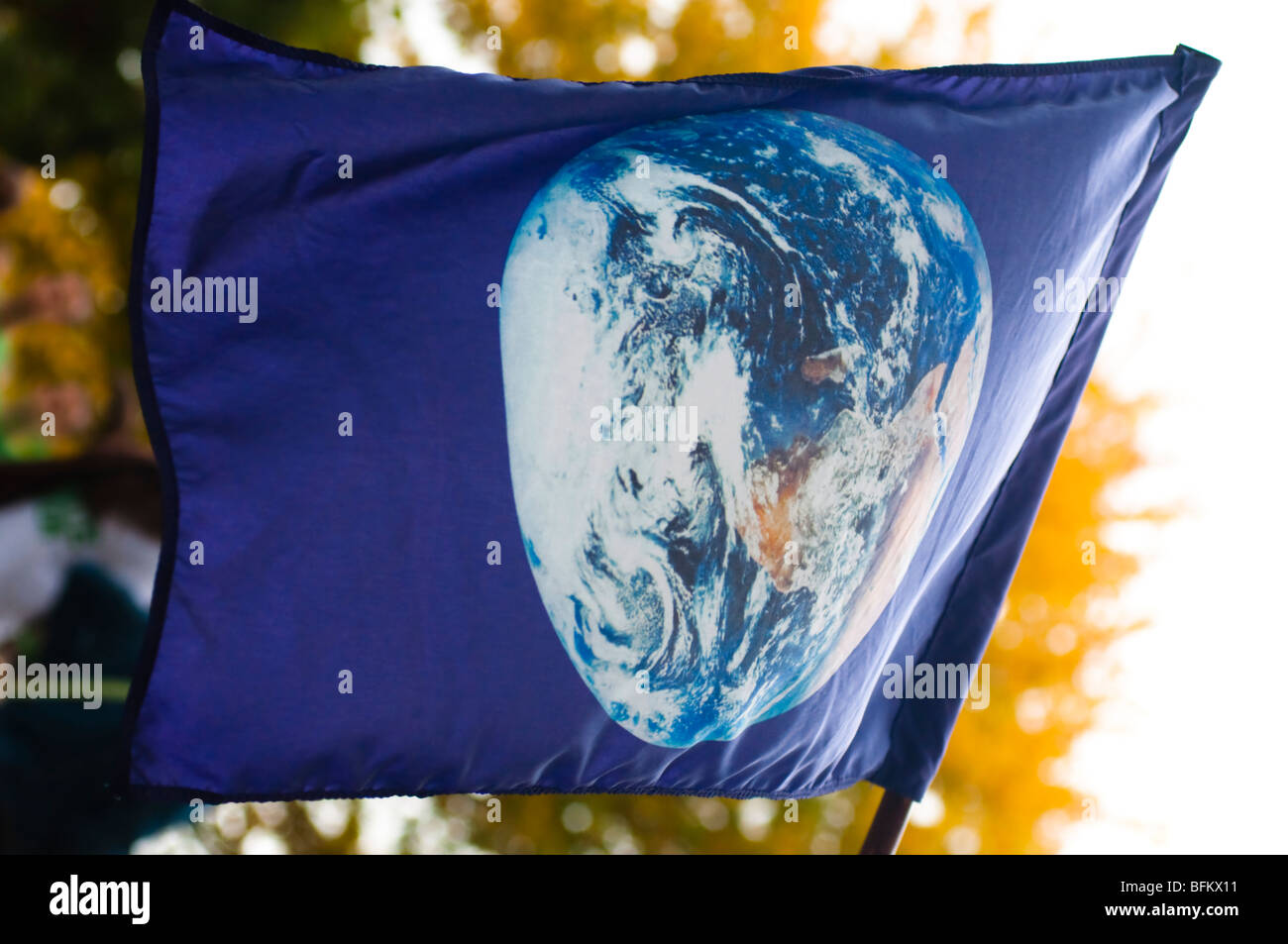 Eine blaue Flagge mit einem Bild der Pflanze Erde fliegt über eine ökologische Protest-Veranstaltung. Stockfoto