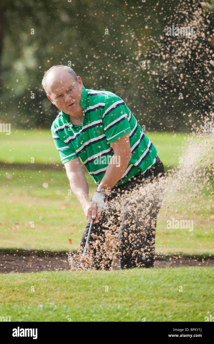Ein weißer Mann, Golf spielen und ein Schuss aus einem Sandbunker Stockfoto