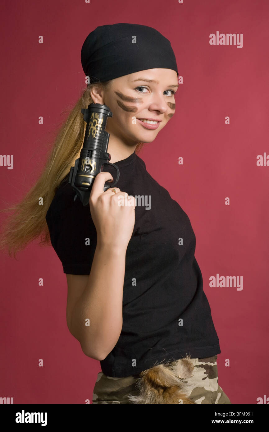 schöne Mädchen in Farbe der Piraten Stand mit Pistole, auf rotem Grund Stockfoto