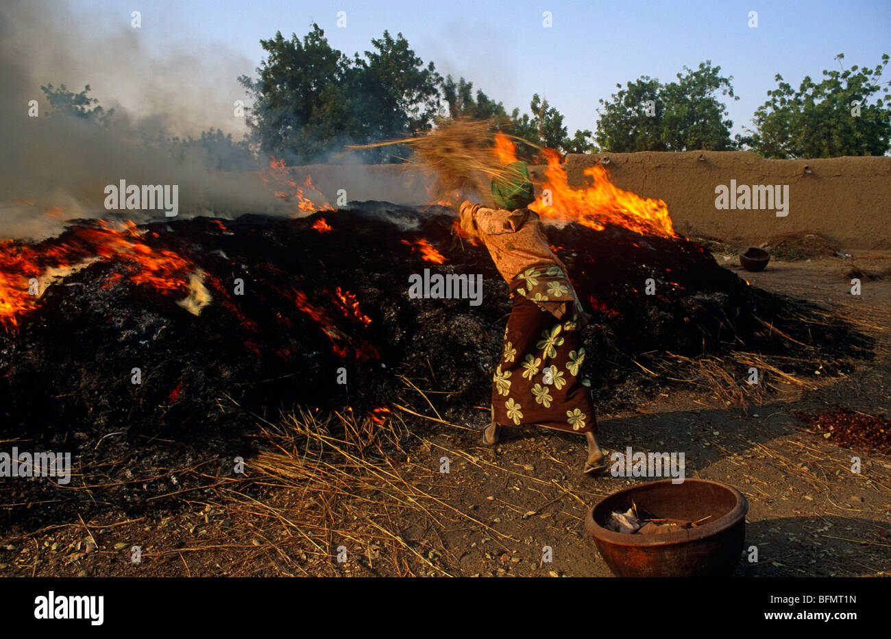 Mali, in der Nähe von Segou, Kalabougou. Eine Frau fügt Anzünden eines Feuers in dem Keramik - wofür dieses Dorf berühmt ist - gebacken wird. Stockfoto