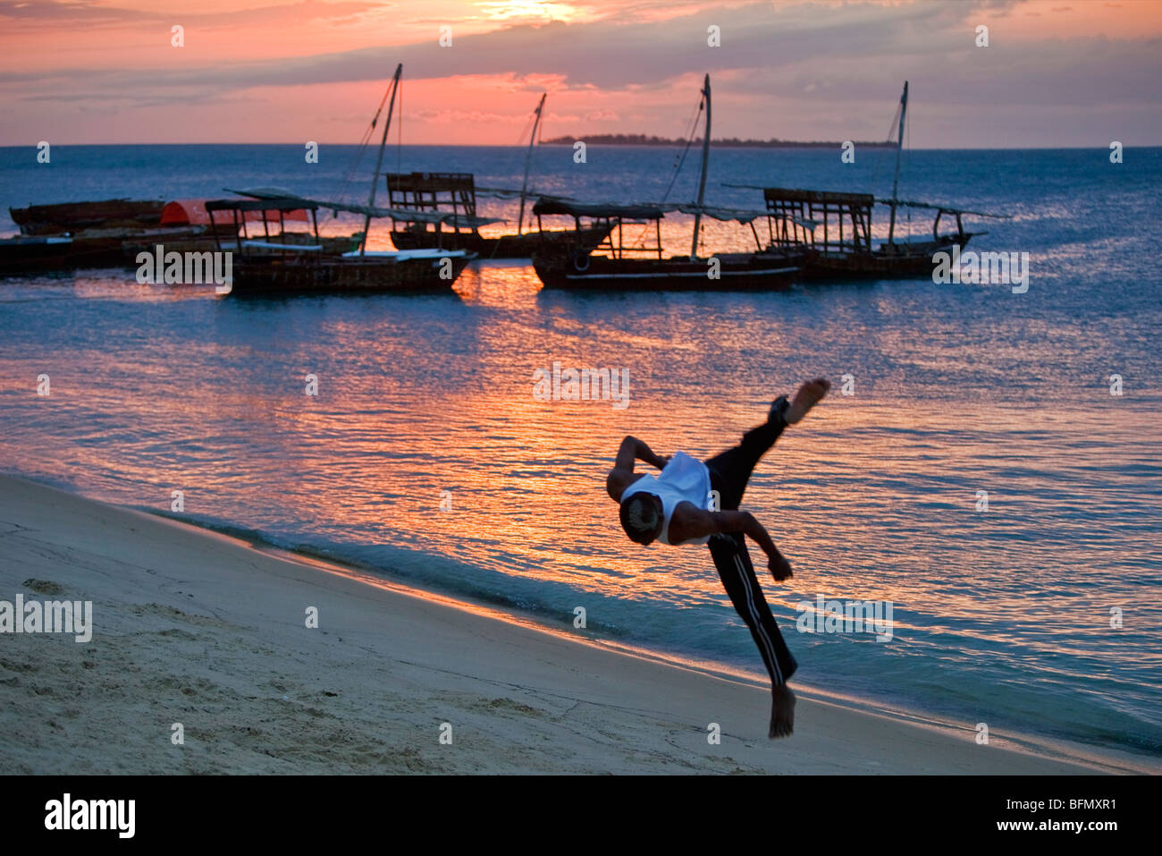 Tansania, Sansibar. Bei Sonnenuntergang, ein Acrobat-Praktiken Saltos auf dem sandigen Strand westlich von Stone Town. Stockfoto