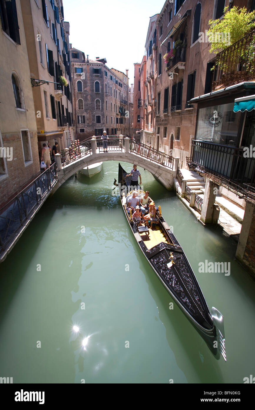 Venedig, Italien. Eine Gondel mit einer jungen Familie geht unter einer Brücke über einen Kanal in die Gassen in der Nähe von Markusplatz entfernt. Stockfoto