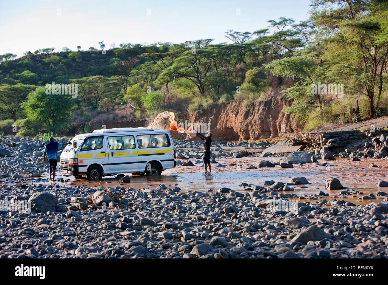 Kenia, Baringo District. Männer waschen einen Minibus, bekannt als ein Matatu, in den schlammigen Gewässern des Flusses Perkerra in der Nähe von Marigat. Stockfoto