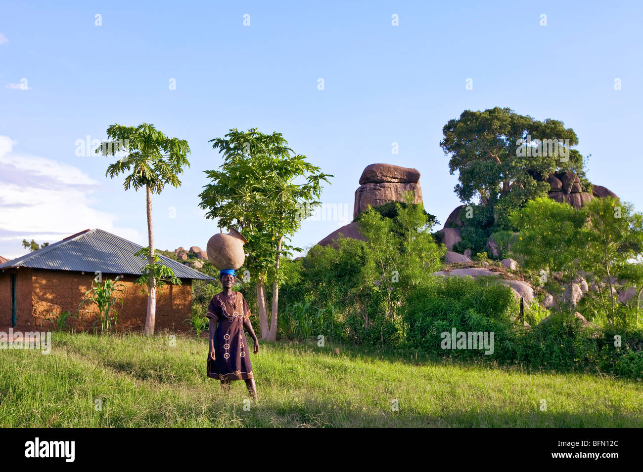 Kenia, Nyanza Bezirk.  Eine Luo Frau trägt ein großes Wasserreservoir zu ihrem Haus in der Nähe von Kit Mikayi Stockfoto