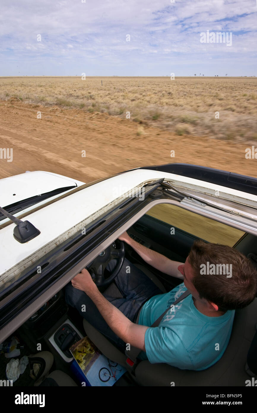 Ein Tourist fährt mit hoher Geschwindigkeit auf einem groben Schotterweg im Outback. Stockfoto