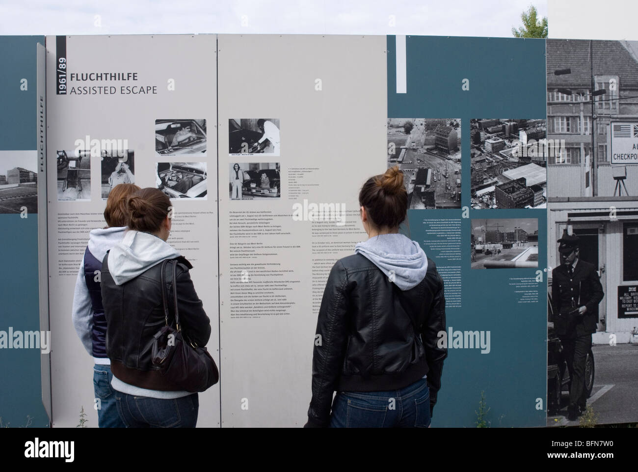 junge Touristen beobachten Paneele in der Friedrichstraße vom Checkpoint Charlie Berlin - Deutschland Stockfoto