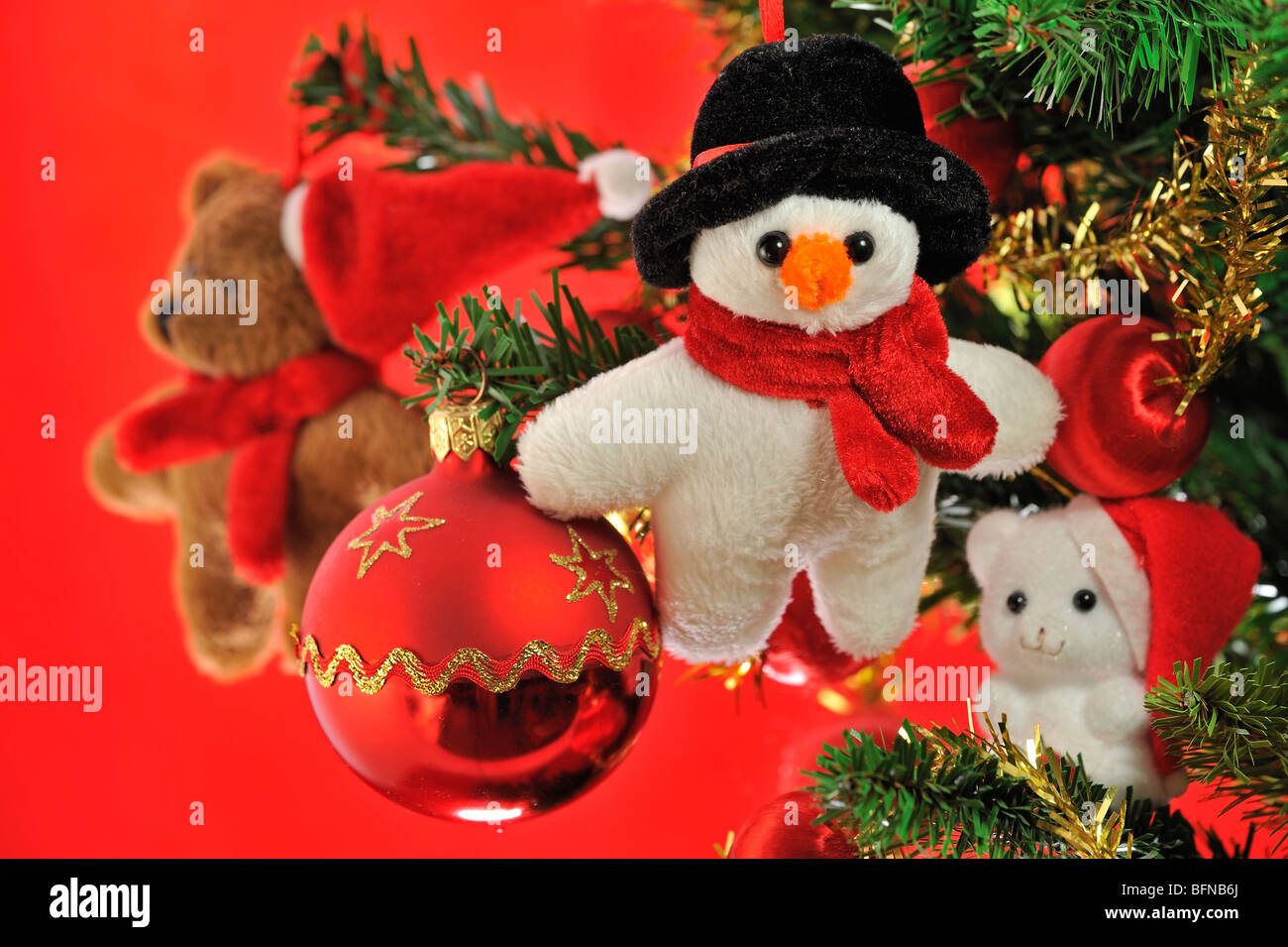 Schneemann, Teddybär und Glocken hängen im Weihnachtsbaum Stockfoto