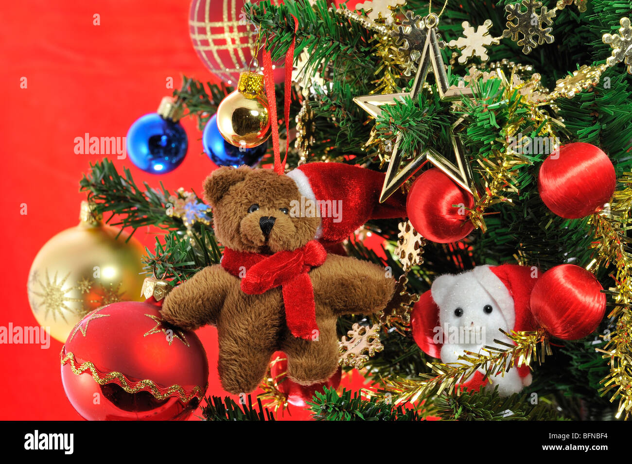 Teddybär-Puppe und Glocken hängen im Weihnachtsbaum Stockfoto