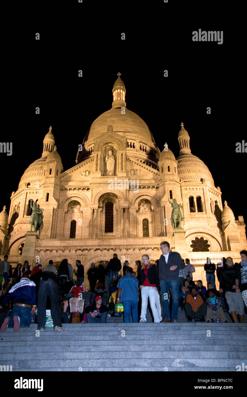 Menschen versammeln sich auf den Stufen der Basilika Sacre-Coeur in der Nacht in Paris, Frankreich. Stockfoto