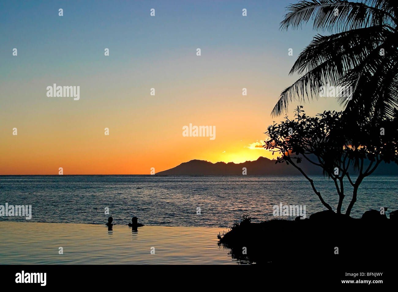 Menschen beobachten Sonnenuntergang beim schweben im Schwimmbad am Rande des Ozeans im romantischen Luxus-Resort in Papeete, Tahiti Stockfoto