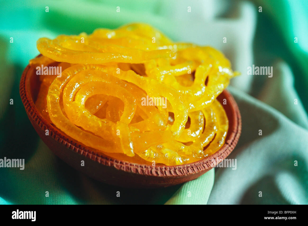 Indische süße Nachspeise snack jalebi gebraten in Zucker in Ton Platte auf grünem Hintergrund Stockfoto