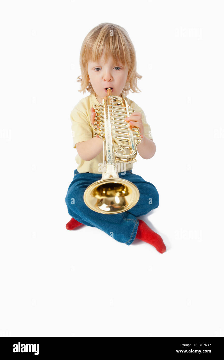 Junge mit langen blonden Haaren mit Spielzeug Trompete spielen Stockfoto