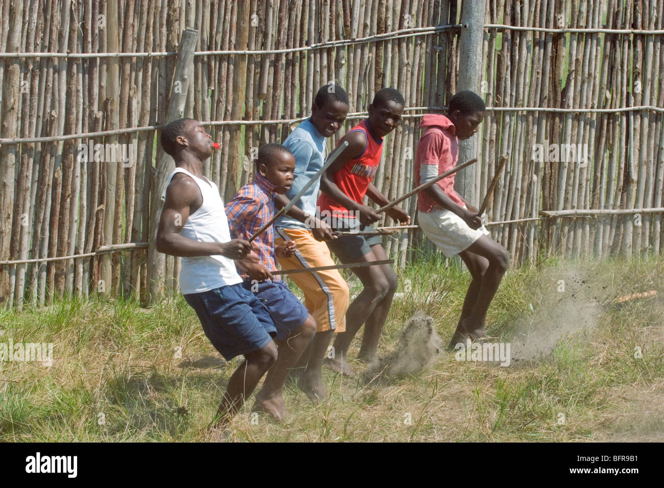 Zulu jungen tanzen mit Stöcken in traditionellen Kral Stockfoto