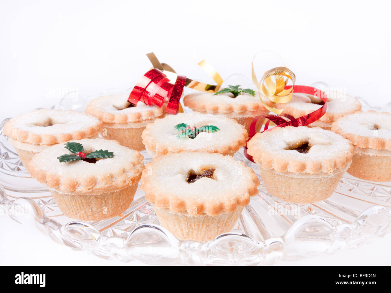 Glasplatte von Sweet Mince Pies verziert mit Bändern und gefälschte Holly. Stockfoto