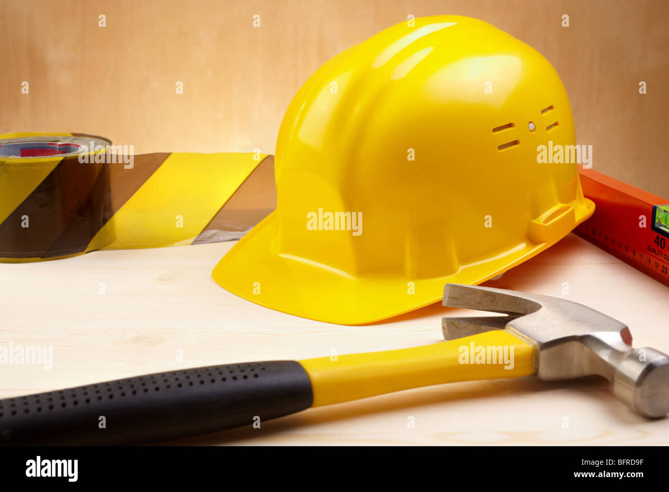 industrielle Konzept mit gelben Bauarbeiterhelm, Hammer und Ebene, selektiven Fokus Stockfoto