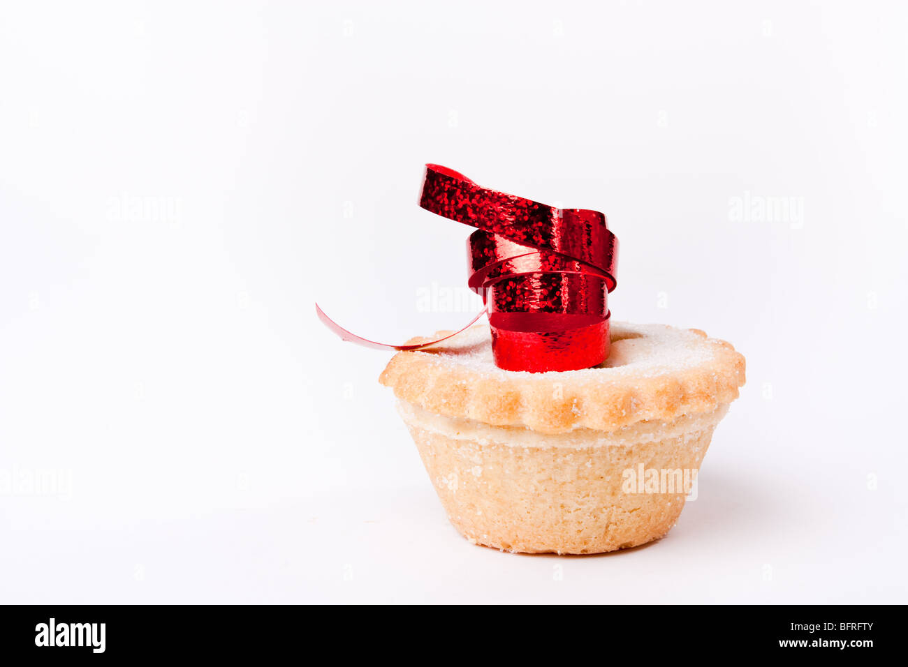Einzelne Sweet Mince Pie isoliert vor weißem Hintergrund mit rotem Band. Stockfoto