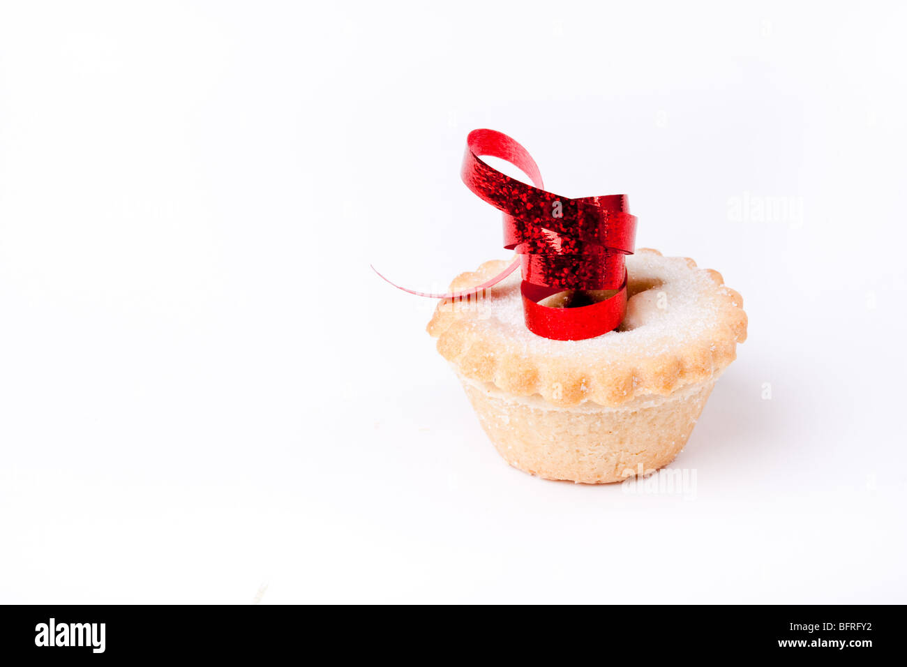 Einzelne Sweet Mince Pie isoliert vor weißem Hintergrund mit rotem Band. Stockfoto
