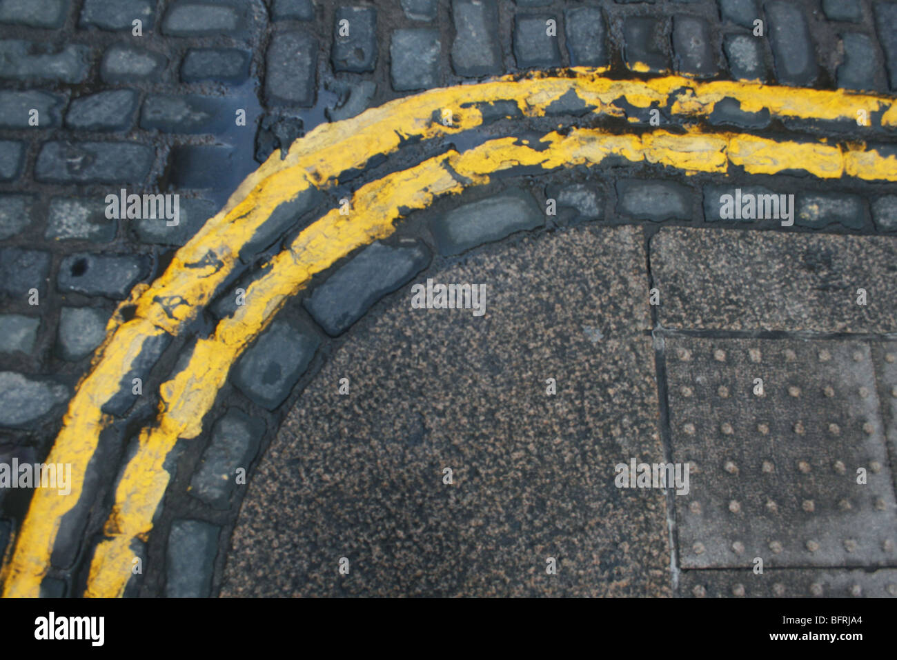 Kopfsteinpflaster Straßenpflaster und doppelte gelbe Linien um die Ecke gehen Stockfoto