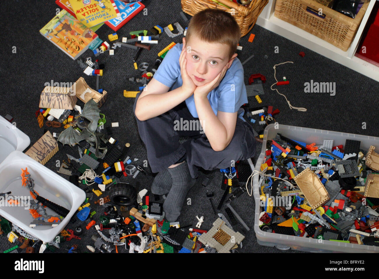 Junge, umgeben von Spielzeug in seinem Schlafzimmer Stockfoto
