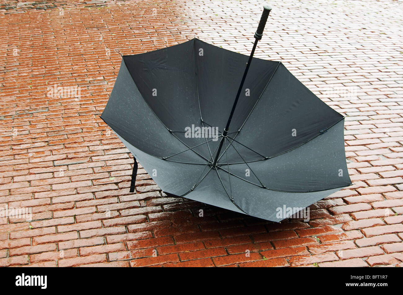 Offenen Regenschirm auf nassem Kopfsteinpflaster liegen Stockfoto