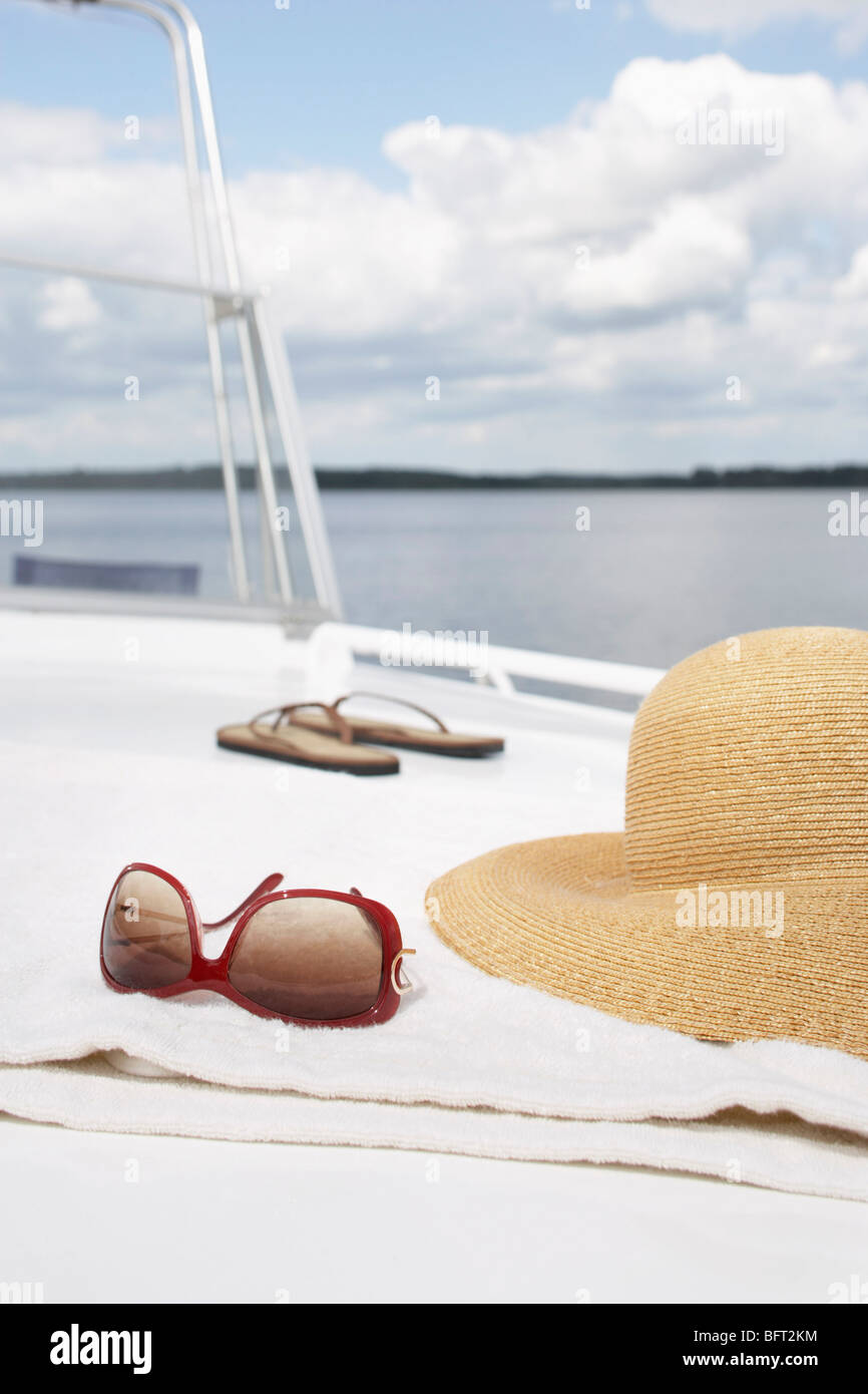 Sonnenbrille, Hut und Flip Flops auf Boot Stockfoto