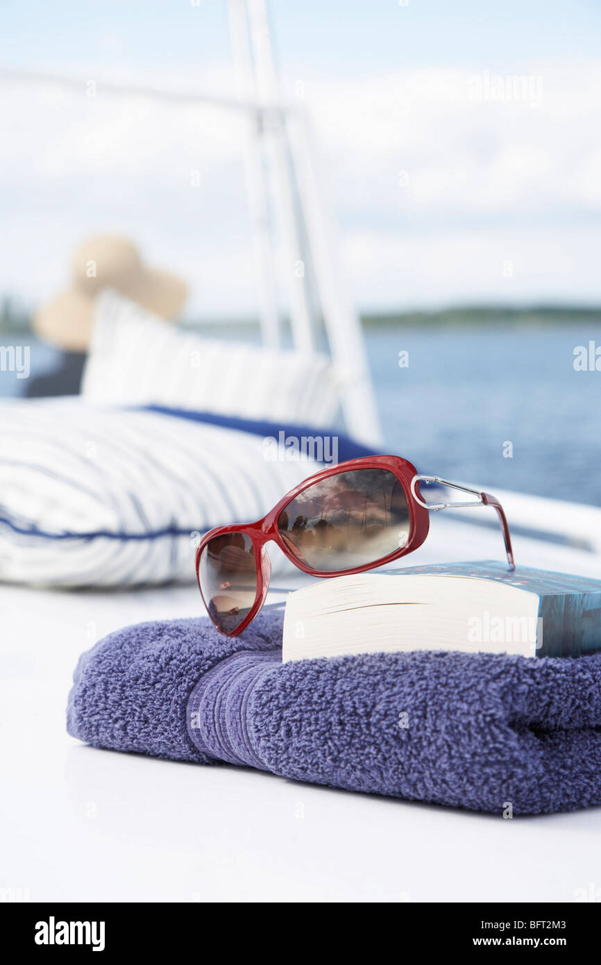 Handtuch, Buch und Sonnenbrille auf Boot Stockfoto