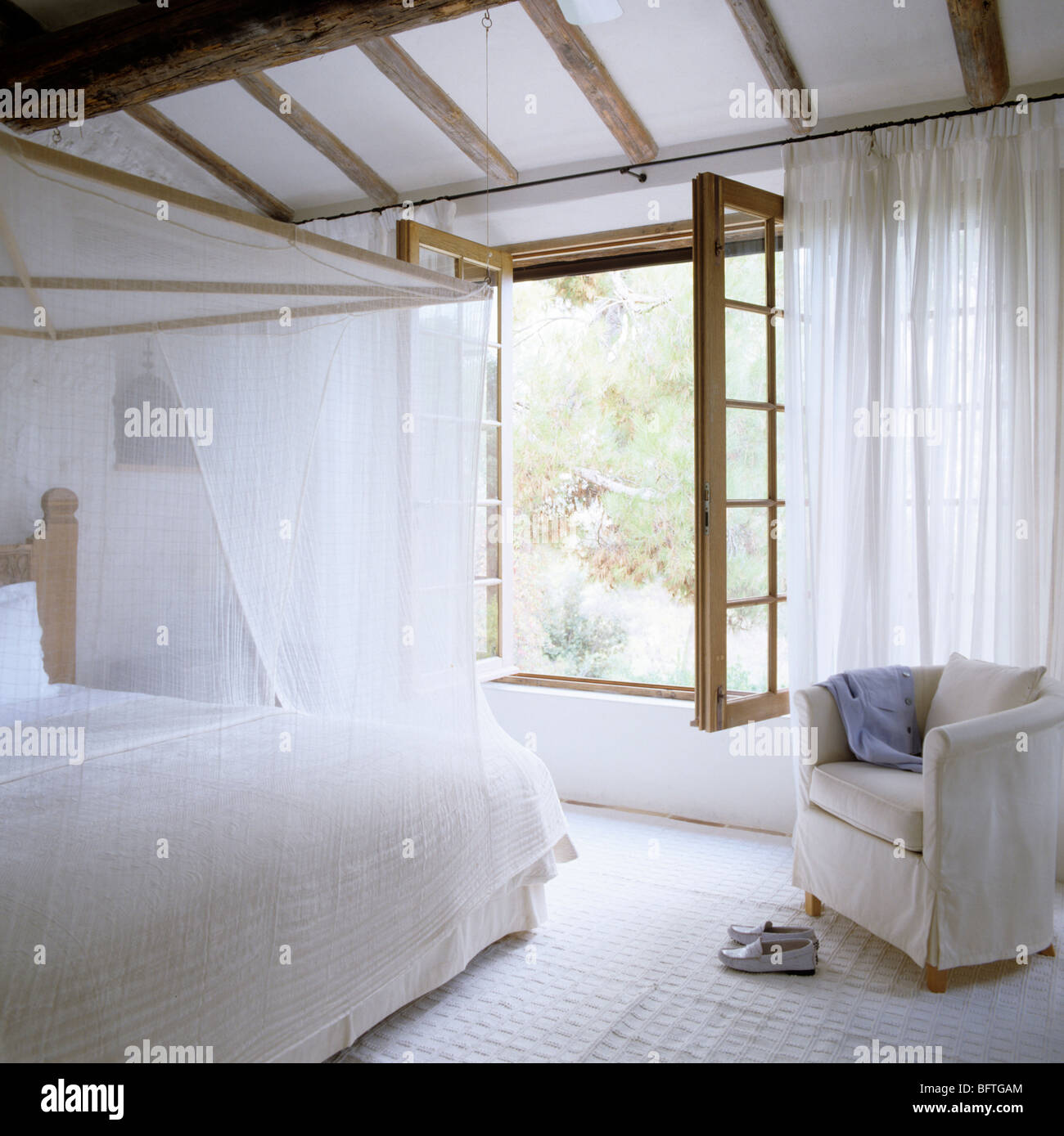Schlafzimmer mit Fenster, weiße Vorhänge und Musselin Bettdecke Stockfoto