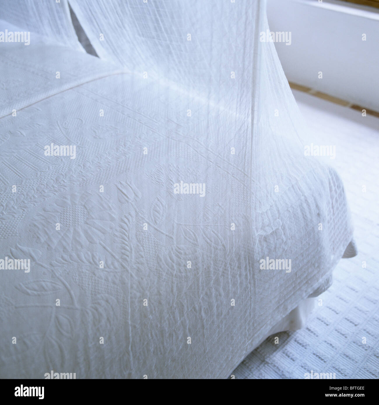 Bett-Ecke mit weißer Bettwäsche und Musselin Netto Stockfoto
