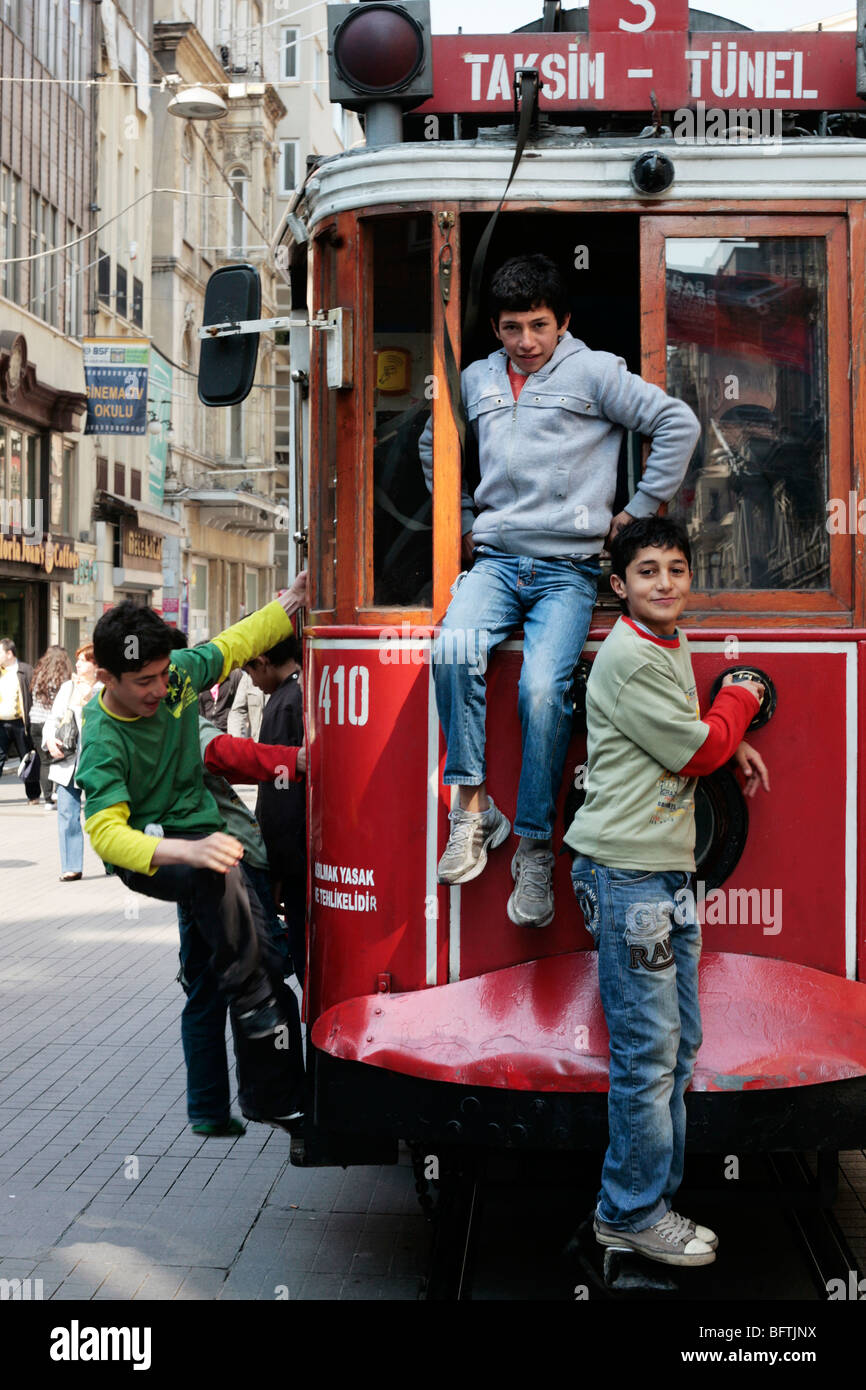 Jungs hängen von der Rückseite der Straßenbahn auf der Istiklal Caddesi in Istanbul Stockfoto