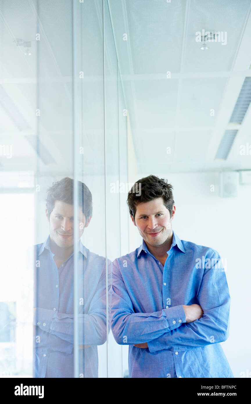 Mann gegen Fenster, Lächeln Stockfoto