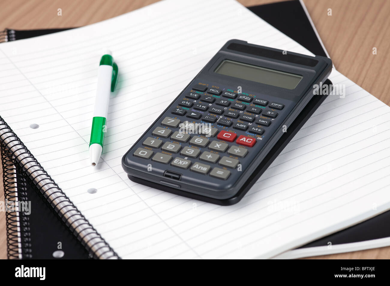 Taschenrechner, Kugelschreiber und Notizblock auf Tabelle Stockfoto
