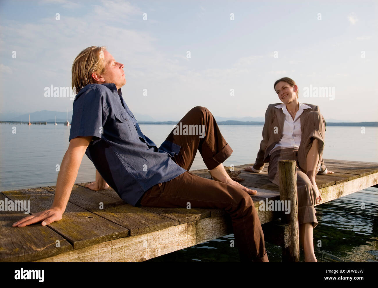 Frau und Mann sitzt auf Pier am See Stockfoto