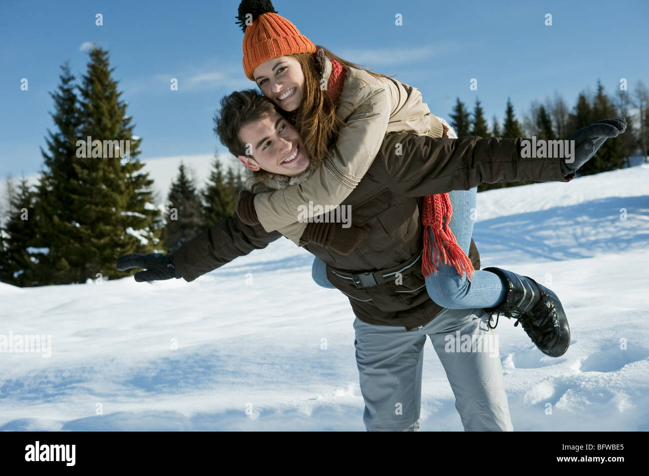 Junge Frau Reiten Huckepack auf jungen Mann im Winter-Szene Stockfoto