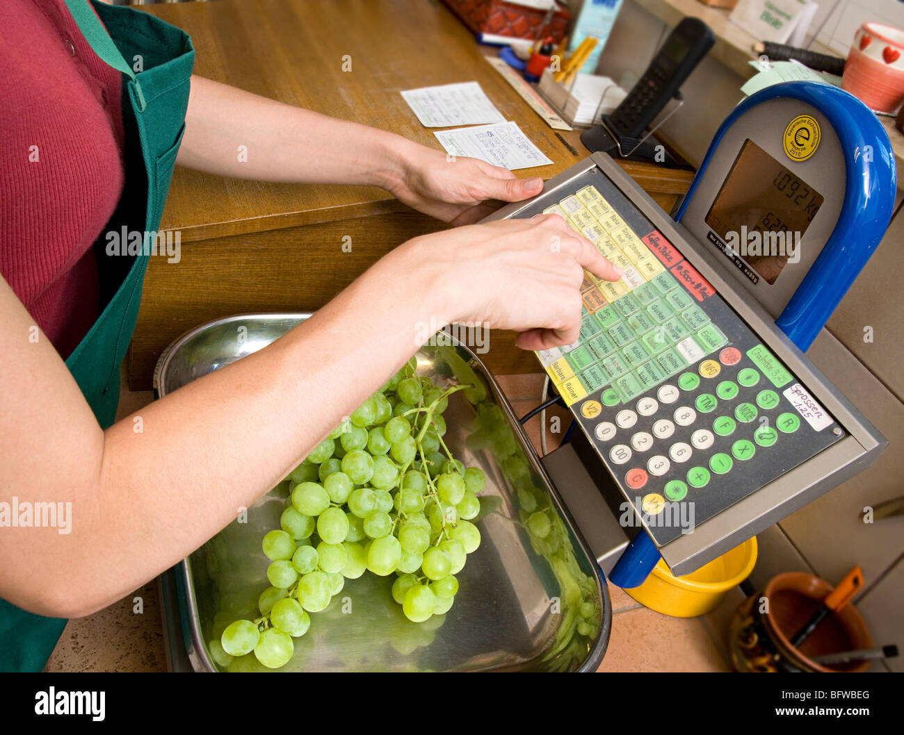 Ladenbesitzer putting Obst im Maßstab Stockfoto