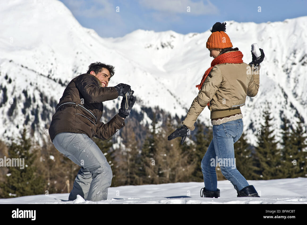 Junger Mann fotografiert junge Frau mit Schneeball im Winter-Szene Stockfoto
