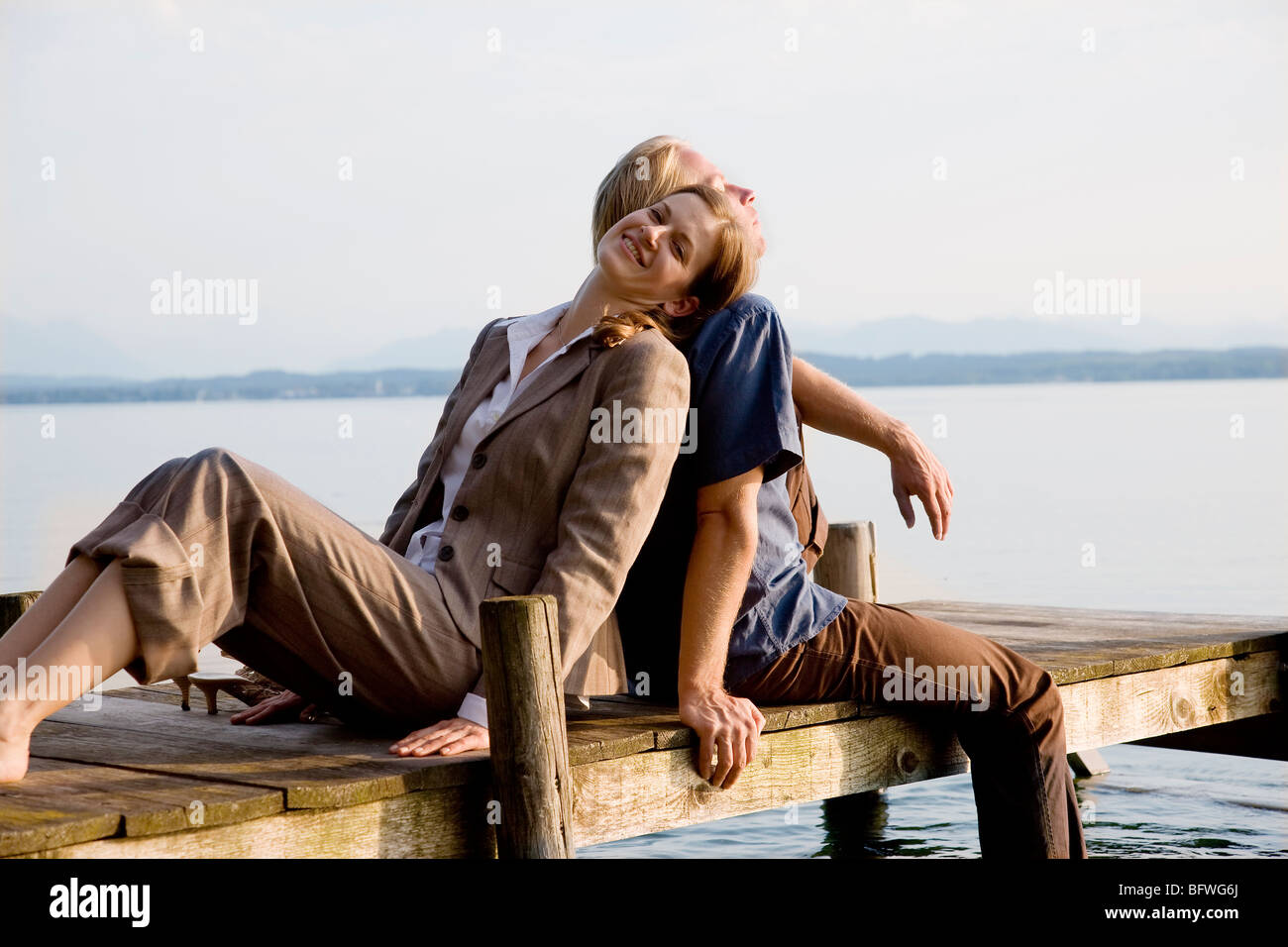 Frau und Mann sitzt auf Pier am See Stockfoto