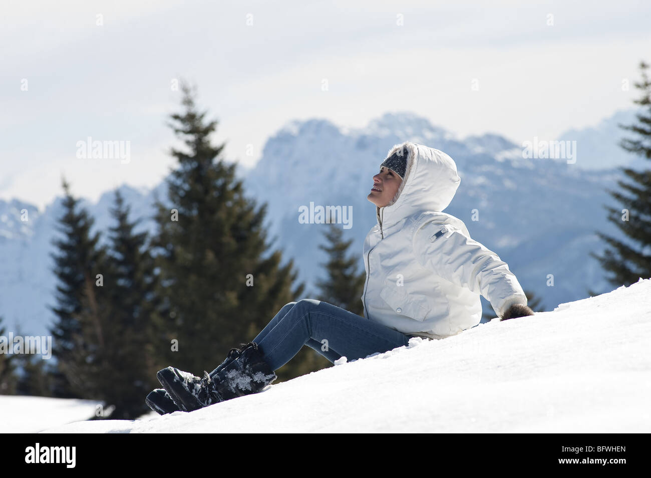 Junge Frau sitzt im Schnee im Winter-Szene Stockfoto