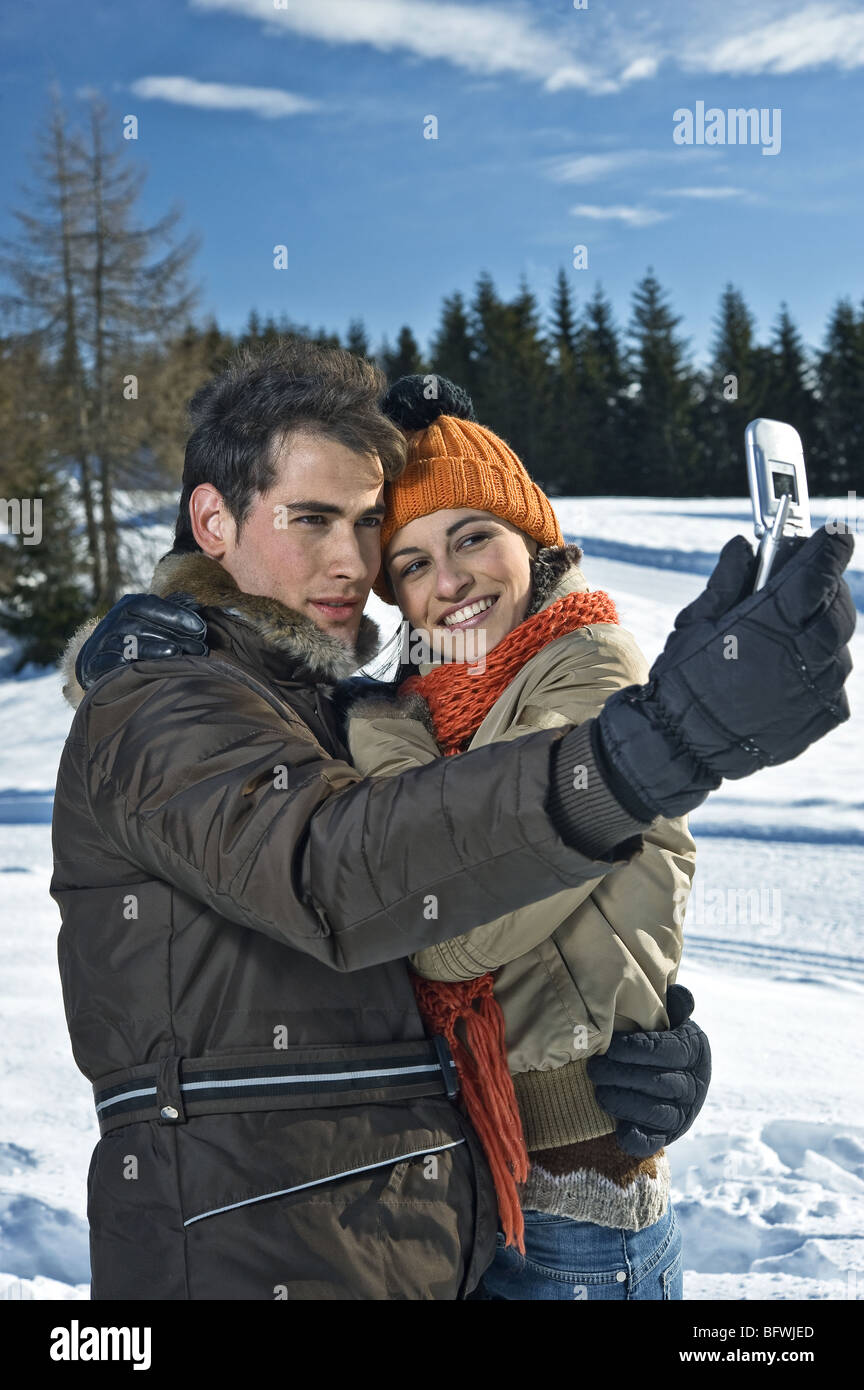 Paar fotografieren sich mit Handy-Kamera im Winter-Szene Stockfoto