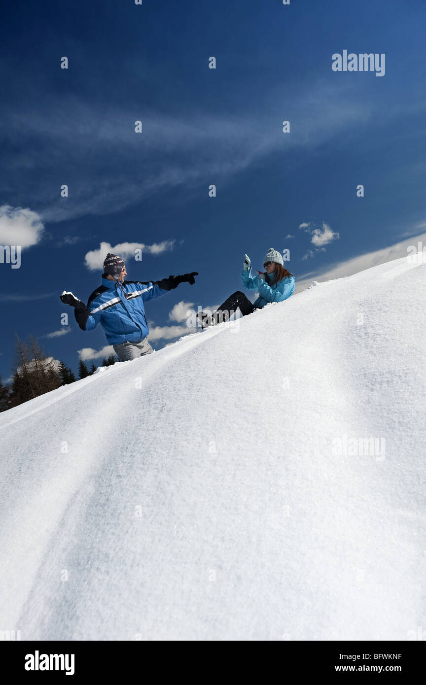 Paar im Schnee, junge Mann werfen Schneeball Stockfoto