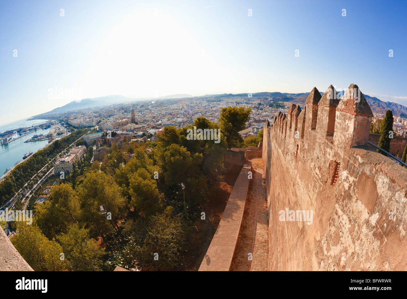 Malaga, Costa Del Sol, Spanien. Mauern und Zinnen der Burg Gibralfaro mit Hafen und Stadt Hintergrund. Stockfoto