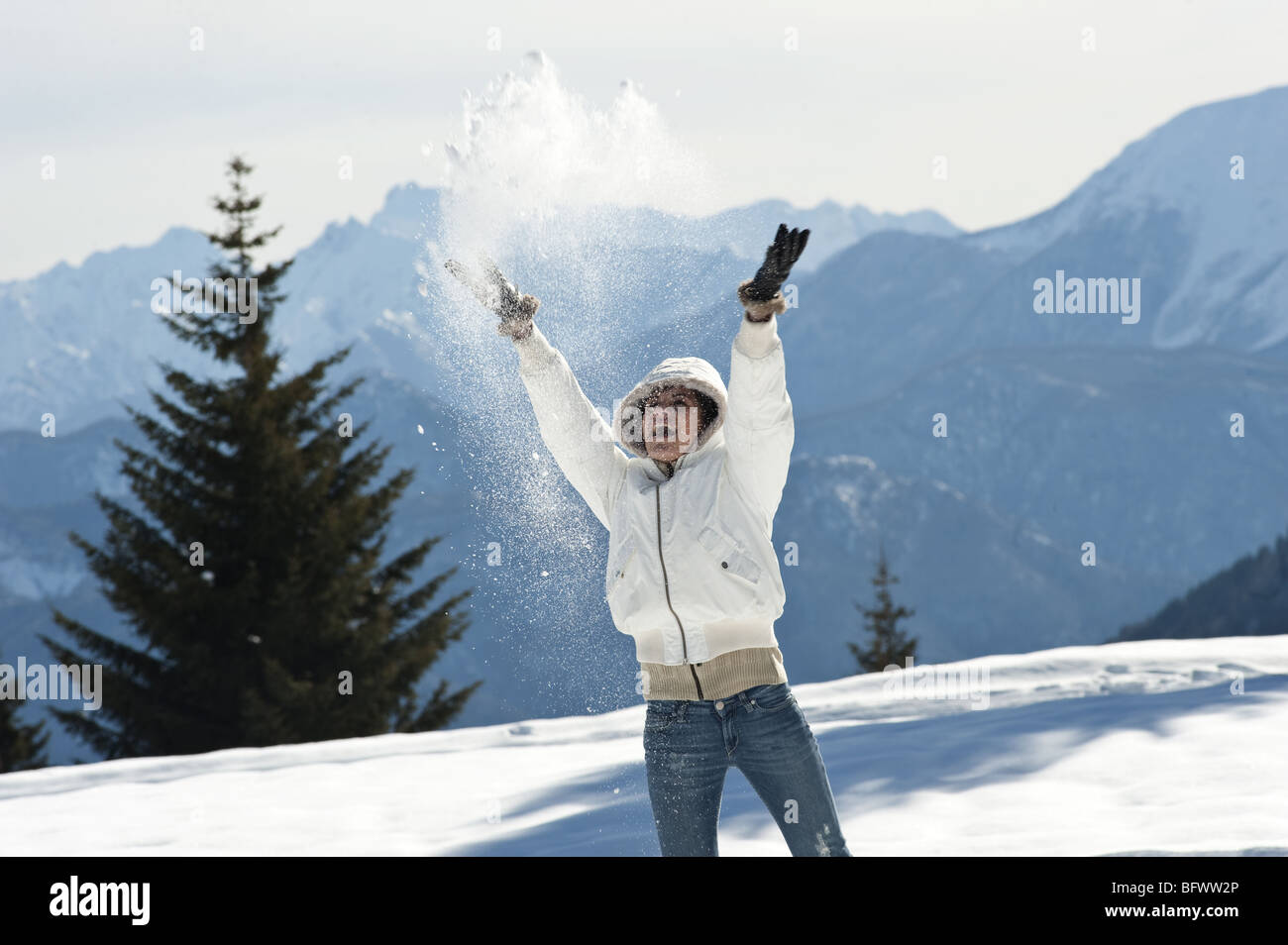 Junge Frau im Winter-Szene mit Schnee-Spray, ausgestreckten Armen Stockfoto