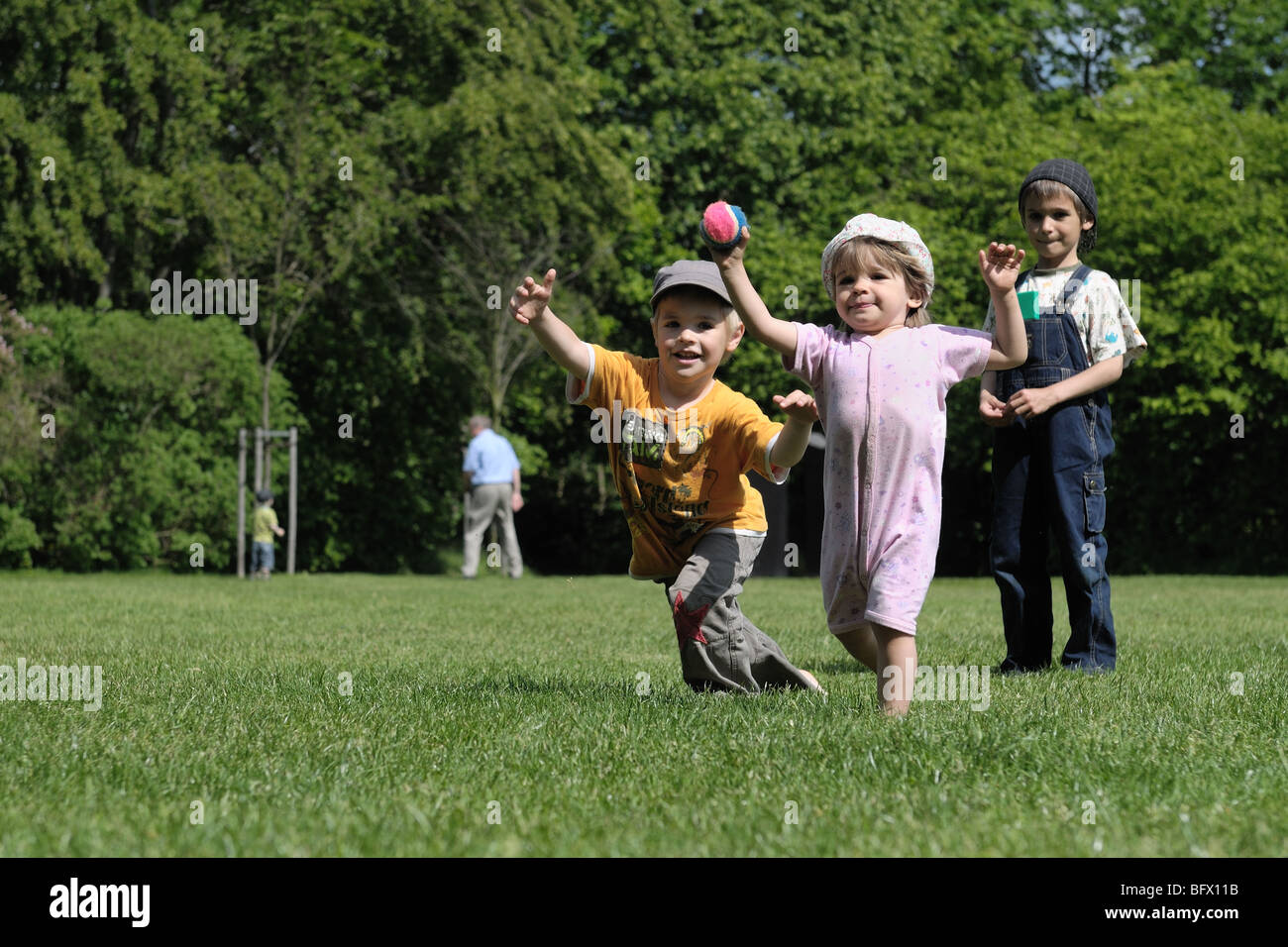 Drei Kinder sind mit einem kleinen Ball spielen. Kleinste entpuppt sich als der schnellste sein. Sie tut ihr Bestes, um den Ball zu retten Stockfoto