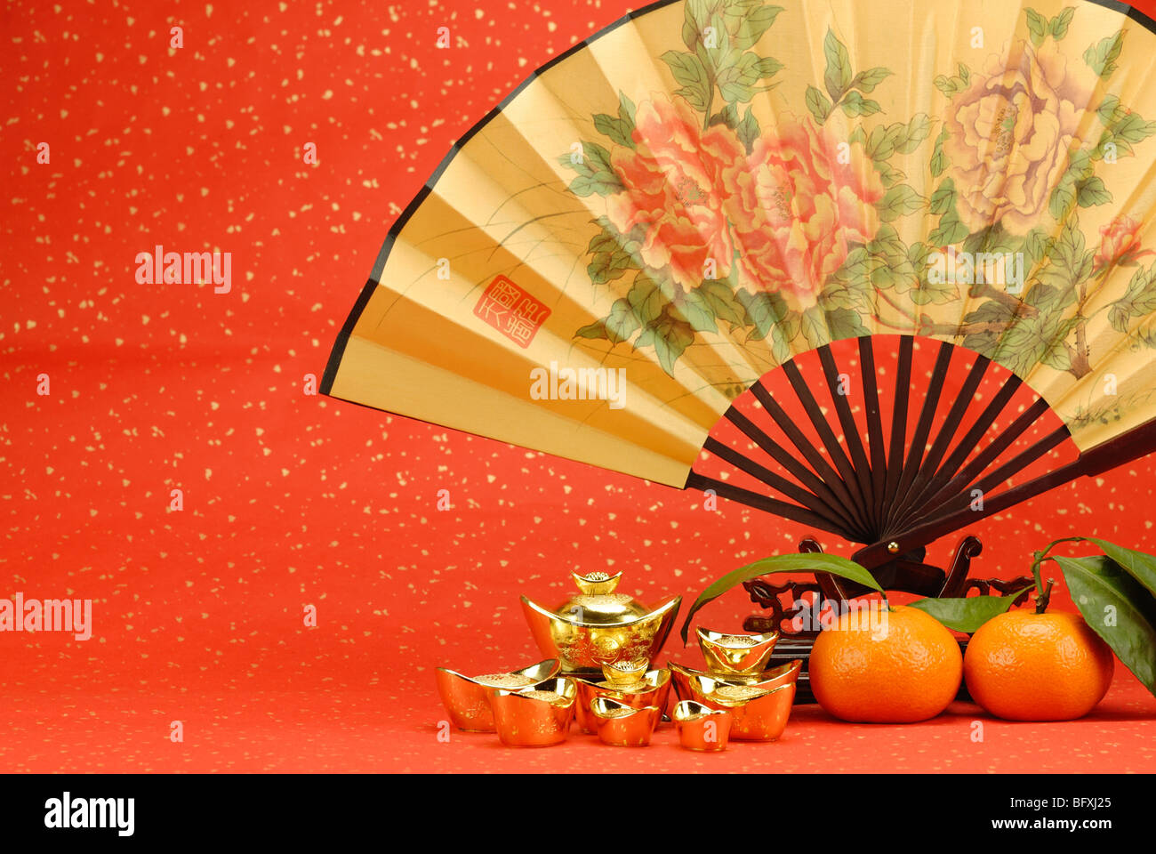 Chinesisches Neujahr Dekoration--traditionelle Fan mit Goldbarren und Orange auf festlichen Hintergrund. Stockfoto